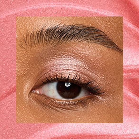 Close-up of an eye area with NYX Professional Makeup Lid Lingerie Cream Eye Pigment in 04 Risky Rose, shown on a rose gold shimmer textured background.
