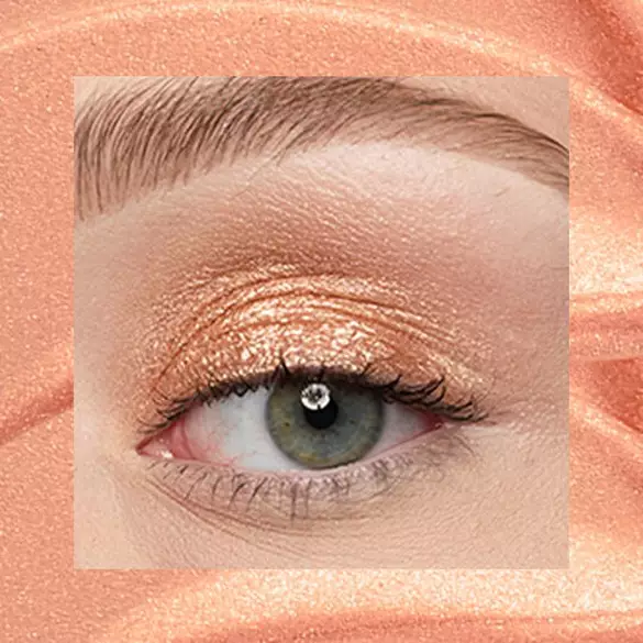 Close-up of an eye area with NYX Professional Makeup Lid Lingerie Cream Eye Pigment in 05 Gold String, shown on a gold shimmer textured background.